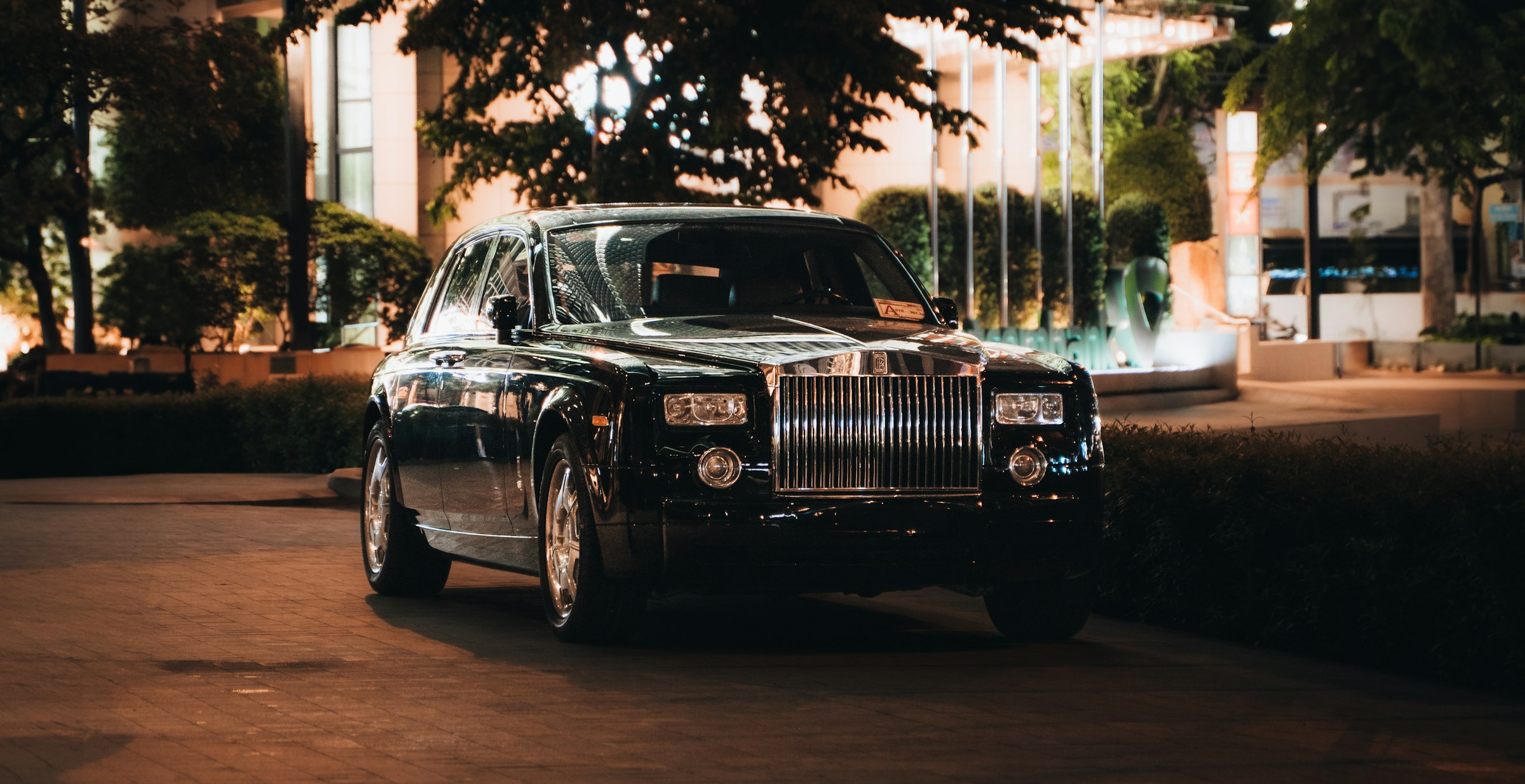 Black Rolls-Royce photographed outside an illuminated building at night